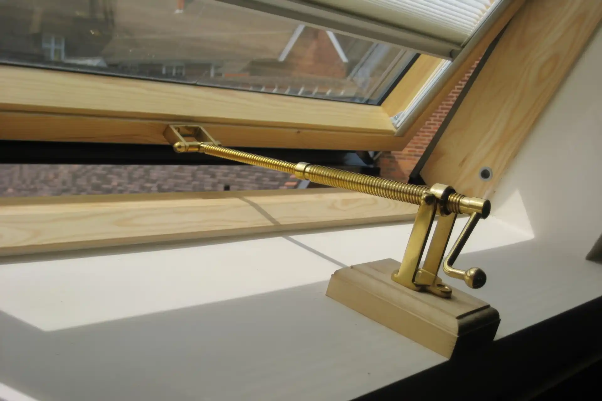 A telescopic screwjack with a handle installed on a pitched roof window